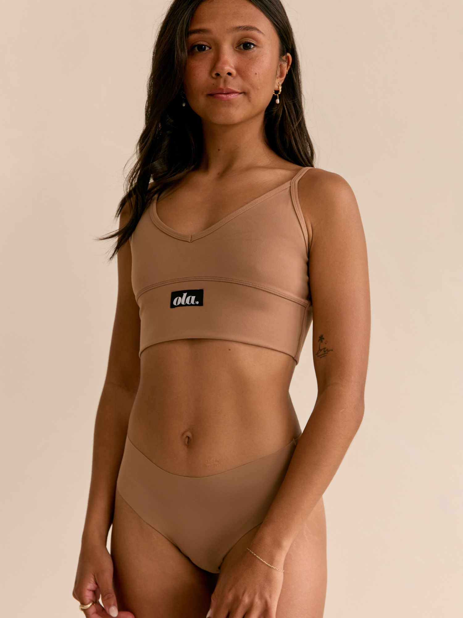 Larni Slightly side on wearing matching Ola set V Crop and Bikini Thong in Hot Fudge