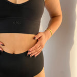 Person wearing a black V Crop and high-waisted seamless underwear with 'ola' branding.
